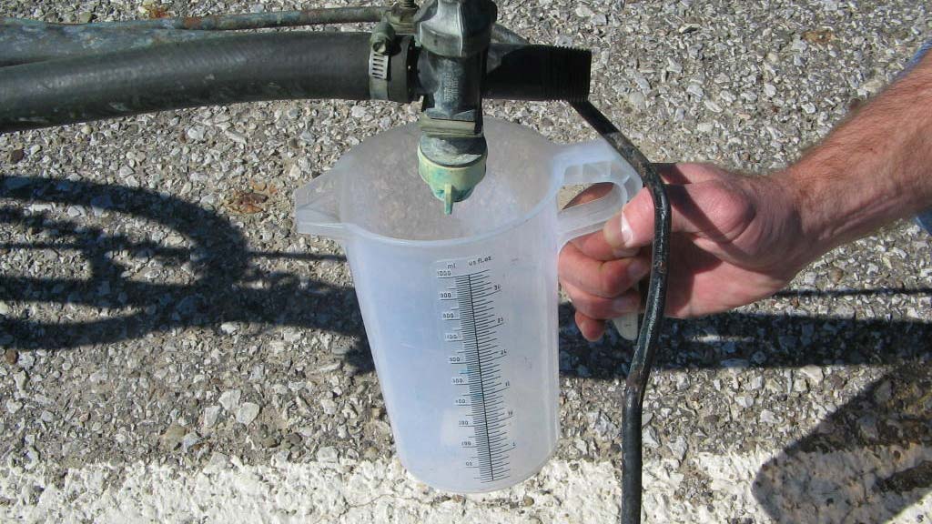 A person holding a measuring cup to check equipment calibration.